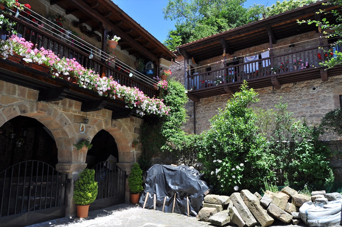 Casas de piedra con balcones de madera llenos de flores en Bárcena Mayor
