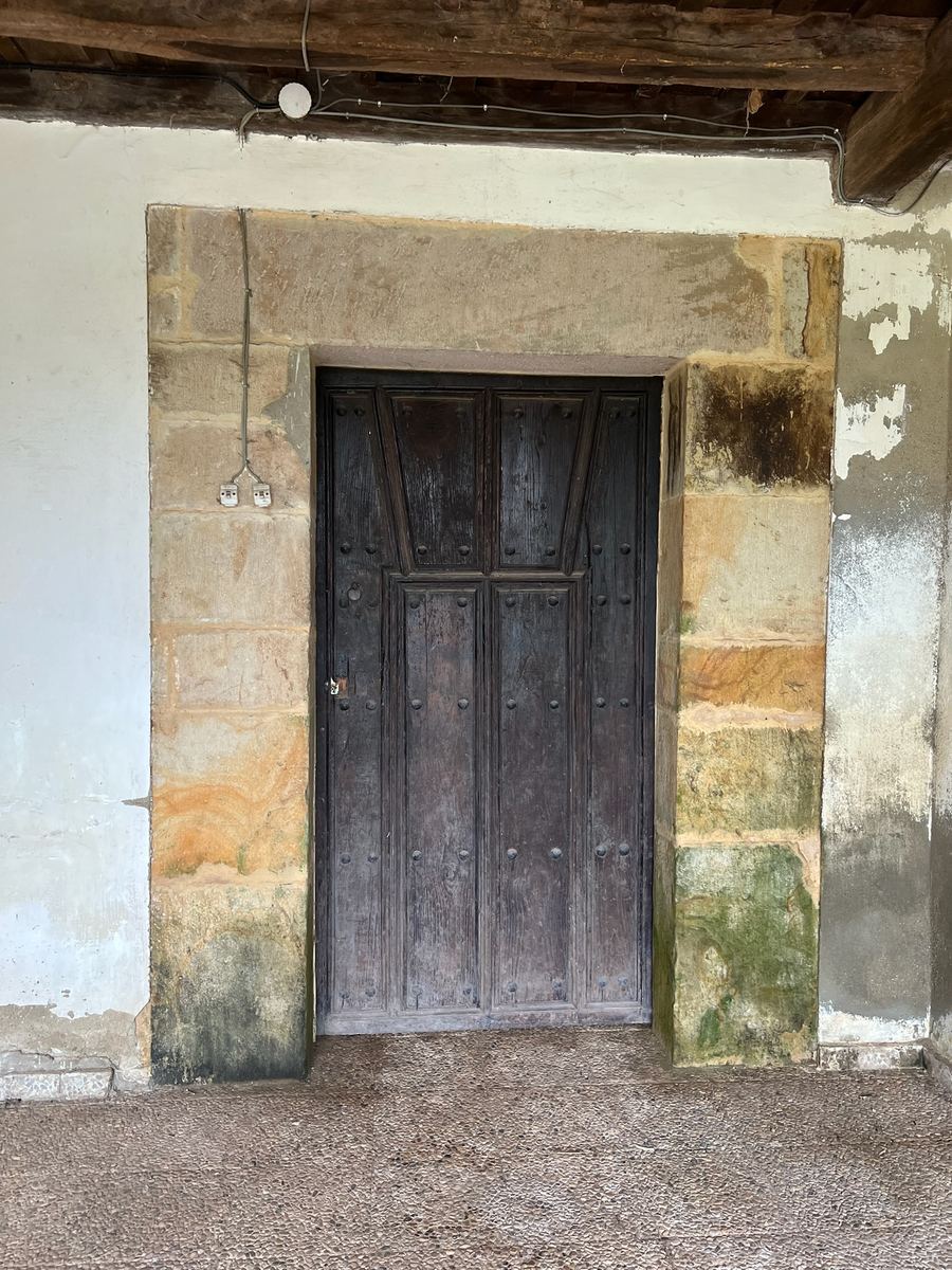 La puerta de madera del cuarto del peregrino, en su marco de piedra