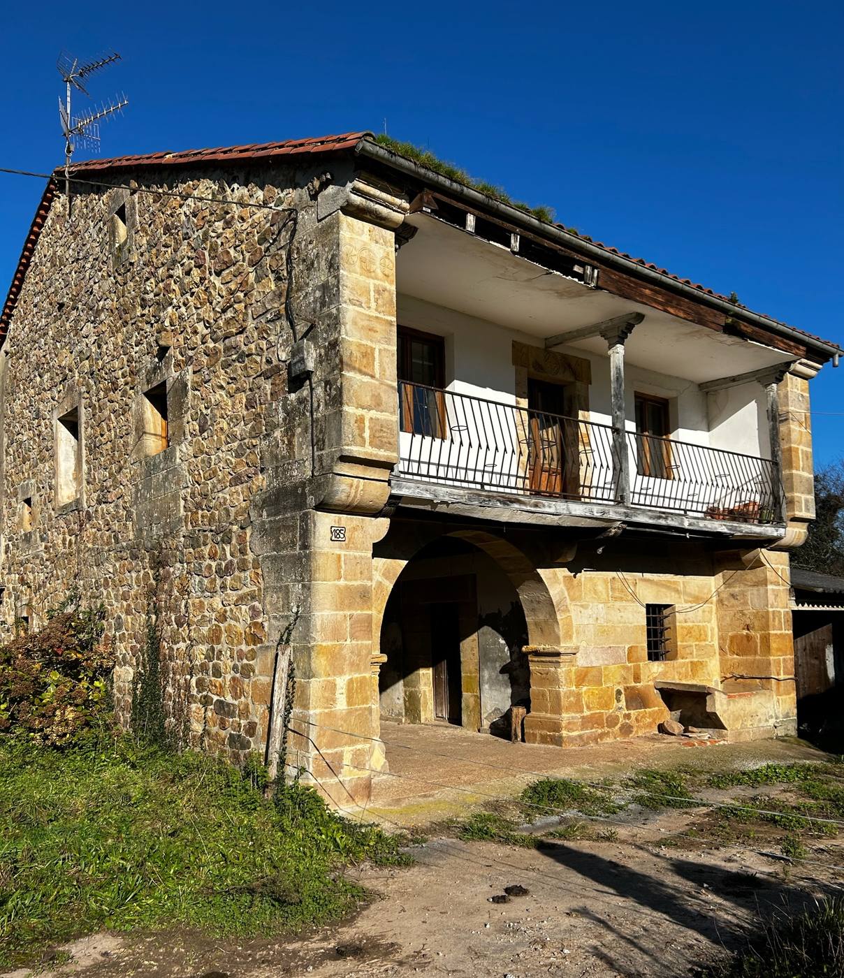 La casona de piedra de Casa Ananta, con su solana de madera y el arco de la entrada, bajo un cielo azul